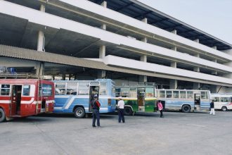 Ônibus coloridos estacionados em uma estação de transporte público urbano.